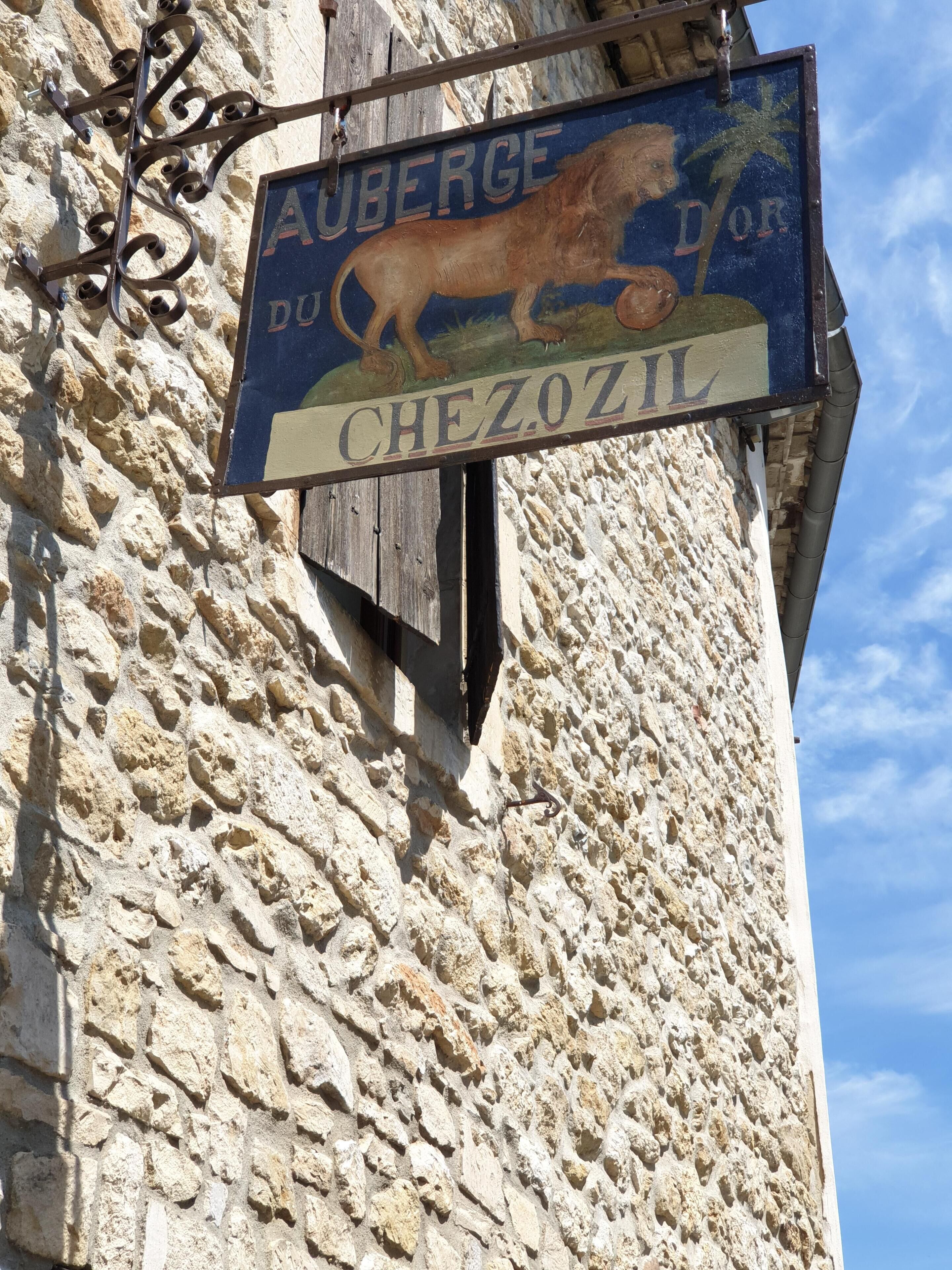 Et skilt med et løvemotiv og en palme, der angiver Auberge du Chefozil.