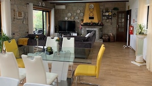 Una sala moderna con una mesa de comedor de vidrio, sofás y una chimenea.