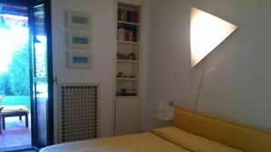 Un dormitorio con cama, una estantería y una lámpara fijada a la pared.