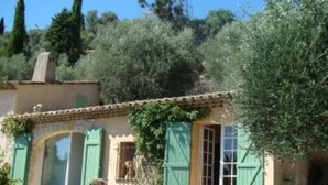 Un bâtiment de style méditerranéen traditionnel, avec un toit en tuiles, des volets verts et une façade en pierre.