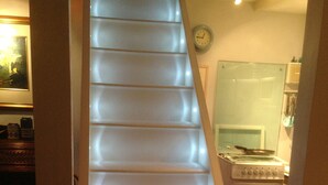 A staircase with illuminated steps leading to a kitchen area. - Charming Fisherman's Cottage in lovely fishing port close to Penzance (Newlyn)