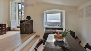 Ein Essbereich mit Blick aufs Meer, ein Holztisch und eine Obstschale.