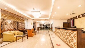 A hotel lobby with a reception desk, seating area, and a decorative partition. - Soaltee Westend Premier (Nepalgunj)