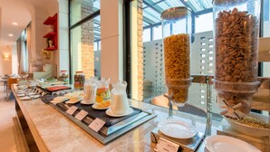 A buffet with various food items and a glass dispenser of cereal. - Soaltee Westend Premier (Nepalgunj)