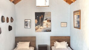 Una habitación con dos camas de madera, una mesita y una lámpara en el techo.