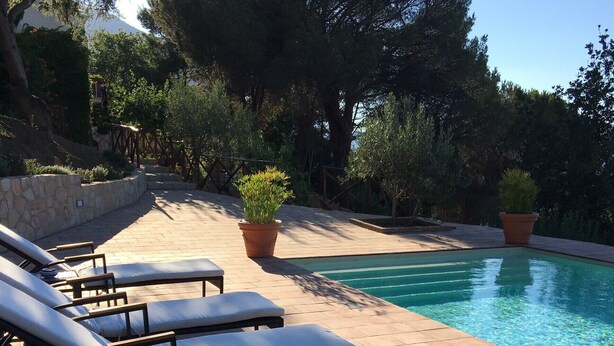 Zona junto a la piscina con sillones de descanso y una alberca.