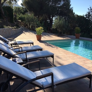 Zona junto a la piscina con sillones de descanso y una alberca.