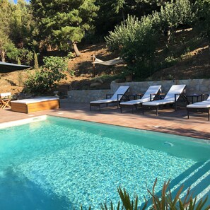 A swimming pool with clear blue water, surrounded by lounge chairs and a stone wall. - Villa with heated pool (Castelbuono (Pa))