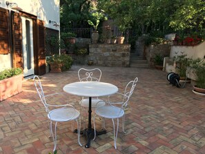 A patio with a round table and four chairs, surrounded by potted plants and a stone wall. - Villa with heated pool (Castelbuono (Pa))