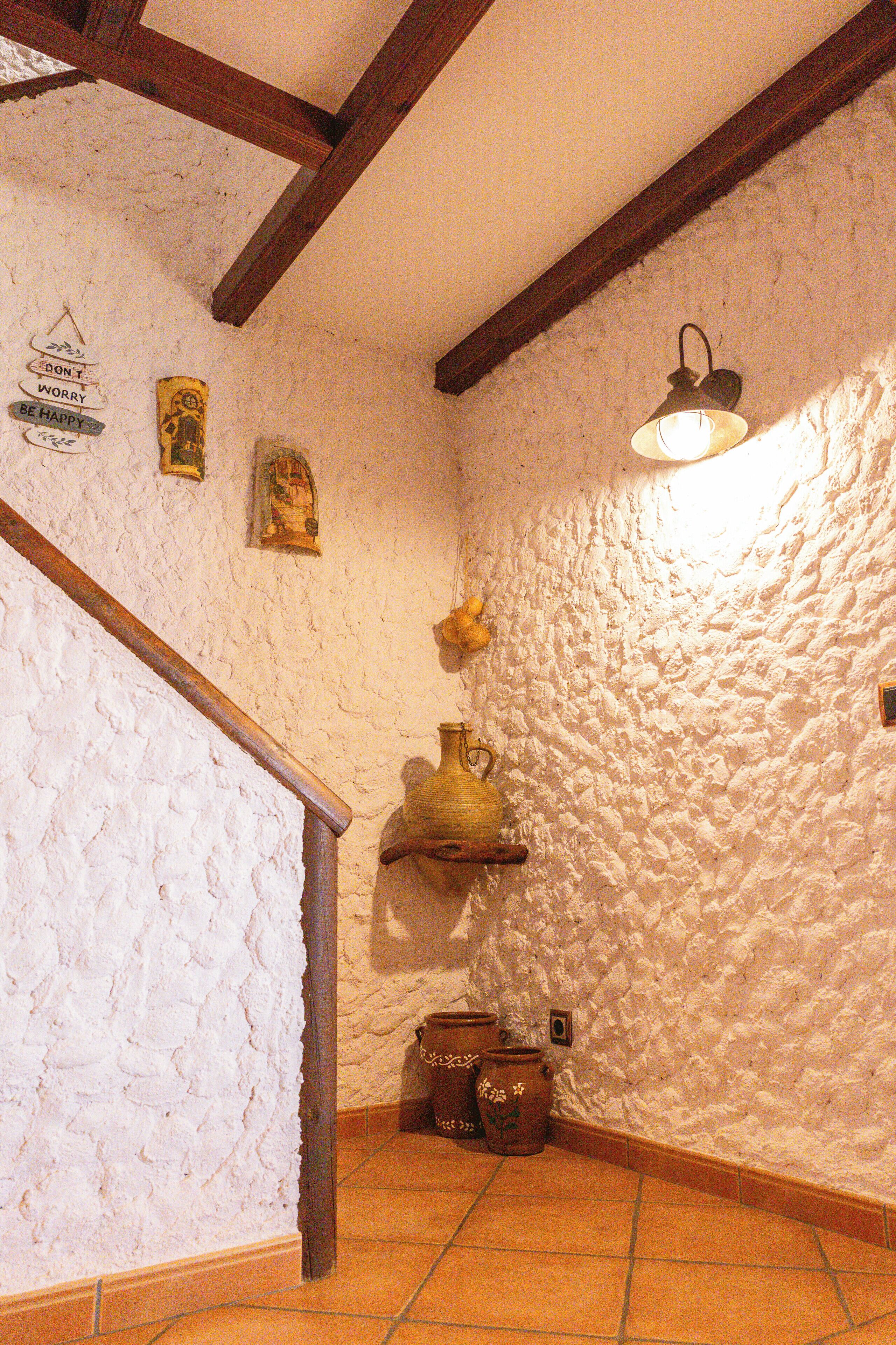 Un interior rústico con paredes de ladrillo visto, vigas de madera y suelo de baldosas.