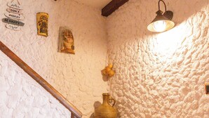 A rustic interior with exposed brick walls, wooden beams, and tiled flooring.