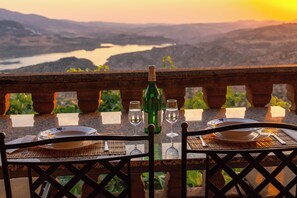 Une table dressée pour deux personnes, avec vue sur un lac et des montagnes en arrière-plan.