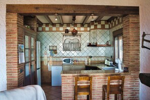 A kitchen with a central island, a refrigerator, a microwave, and a toaster. There are wooden chairs and a calendar on the wall. - The Golden Valley: A rural paradise in the Sierra de Cádiz. (El Gastor)
