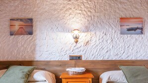 A room with two beds, a wooden nightstand, a wall-mounted lamp, and two framed pictures.