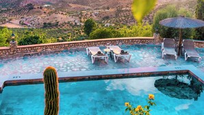 A swimming pool with lounge chairs and a view of a valley.