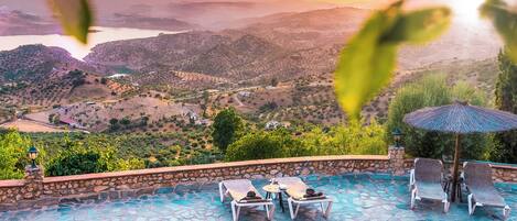 A swimming pool with lounge chairs and a view of a valley.