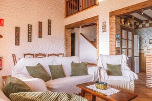 A cozy living room with a white sofa, green cushions, a wooden coffee table, and a brick fireplace. - The Golden Valley: A rural paradise in the Sierra de Cádiz. (El Gastor)