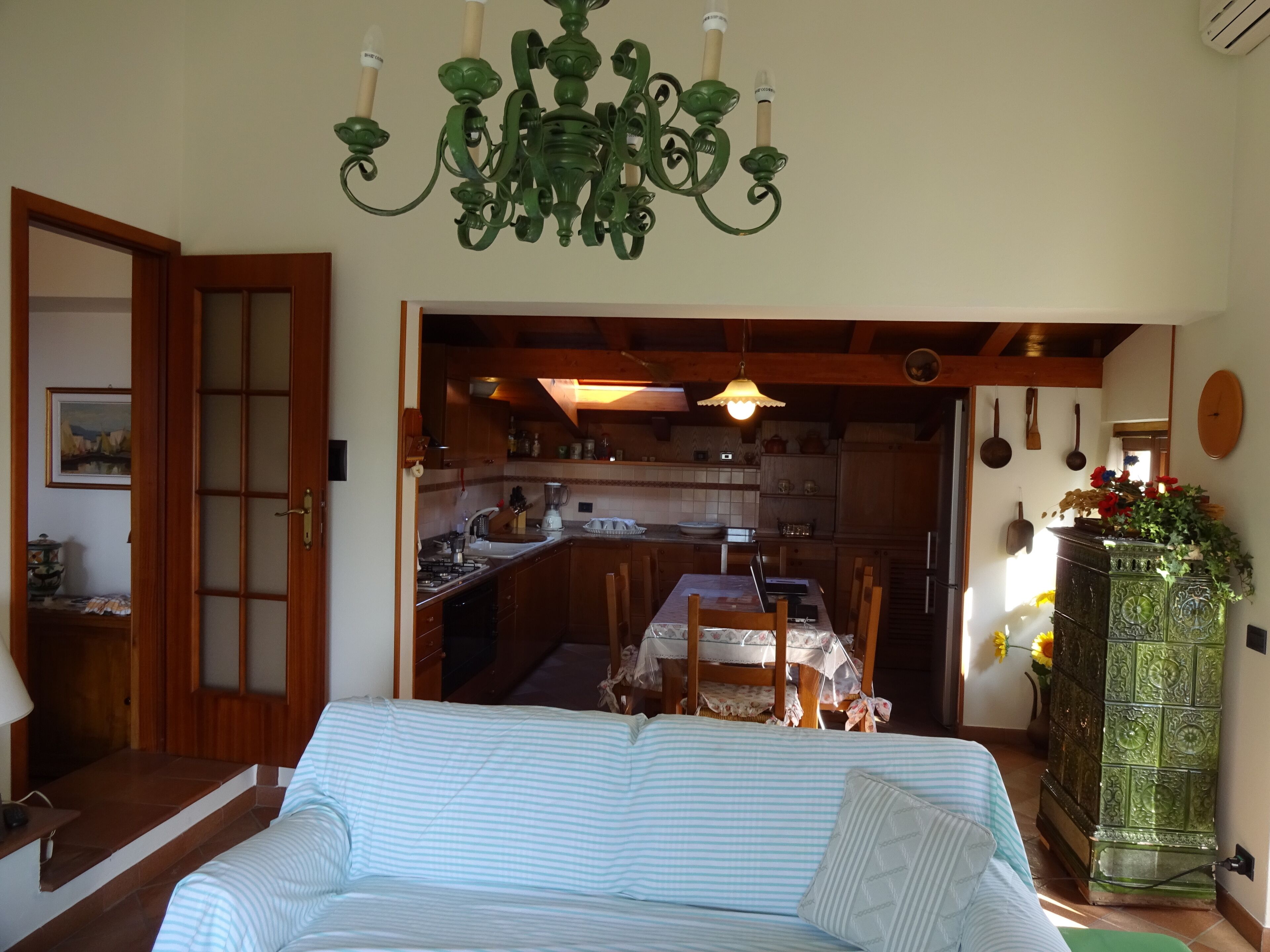 Ein Zimmer mit einem Bett, einem Esstisch mit Stühlen, einer Küchenzeile und einer Kandelaber.