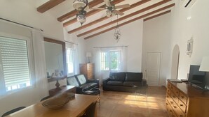 Amplia sala de estar con una mesa de comedor de madera, un sofá y un televisor.