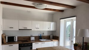Una cocina moderna con armarios blancos, microondas, tostadora, lavamanos y encimera de madera.