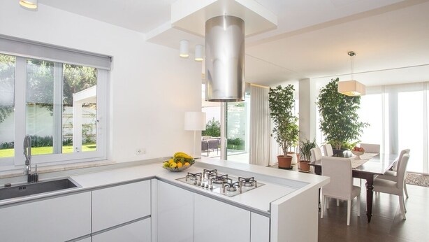 A modern kitchen with a central island, large windows, and a dining area with a table and chairs. - Modern detached villa near the beach of Mondello (Palermo)