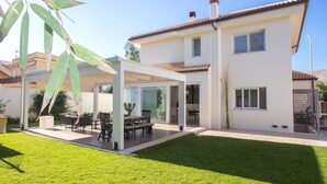 A modern two-story house with a covered patio, a well-maintained lawn, and a clear sky. - Modern detached villa near the beach of Mondello (Palermo)