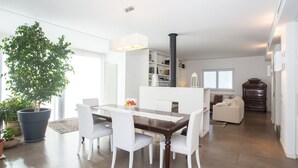 A modern dining area with a large dining table, white chairs, and a potted plant. - Modern detached villa near the beach of Mondello (Palermo)