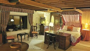 A traditional room with a bed, a desk, a chair, and a mirror.