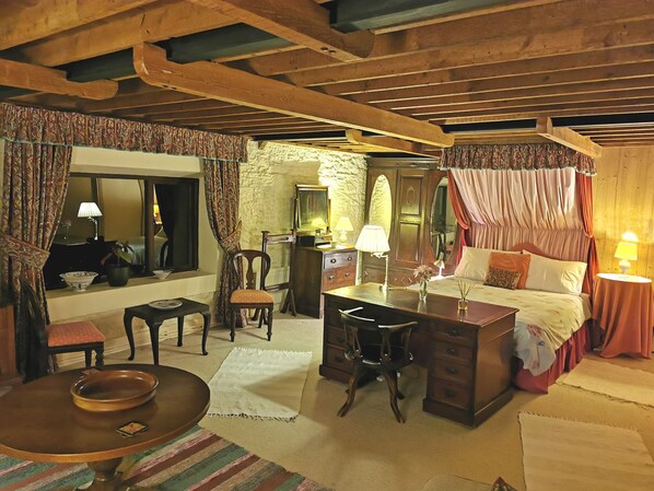 A traditional room with a bed, a desk, a chair, and a mirror.
