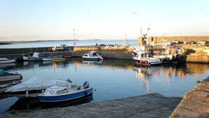 A harbor with boats docked, a stone quay, and a clear sky.