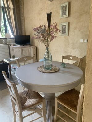 Un tavolo rotondo da pranzo con un vaso di fiori, circondato da quattro sedie con sedili in vimini.