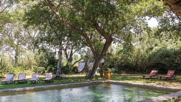 Un área de piscina con sillones reclinables y una pérgola.