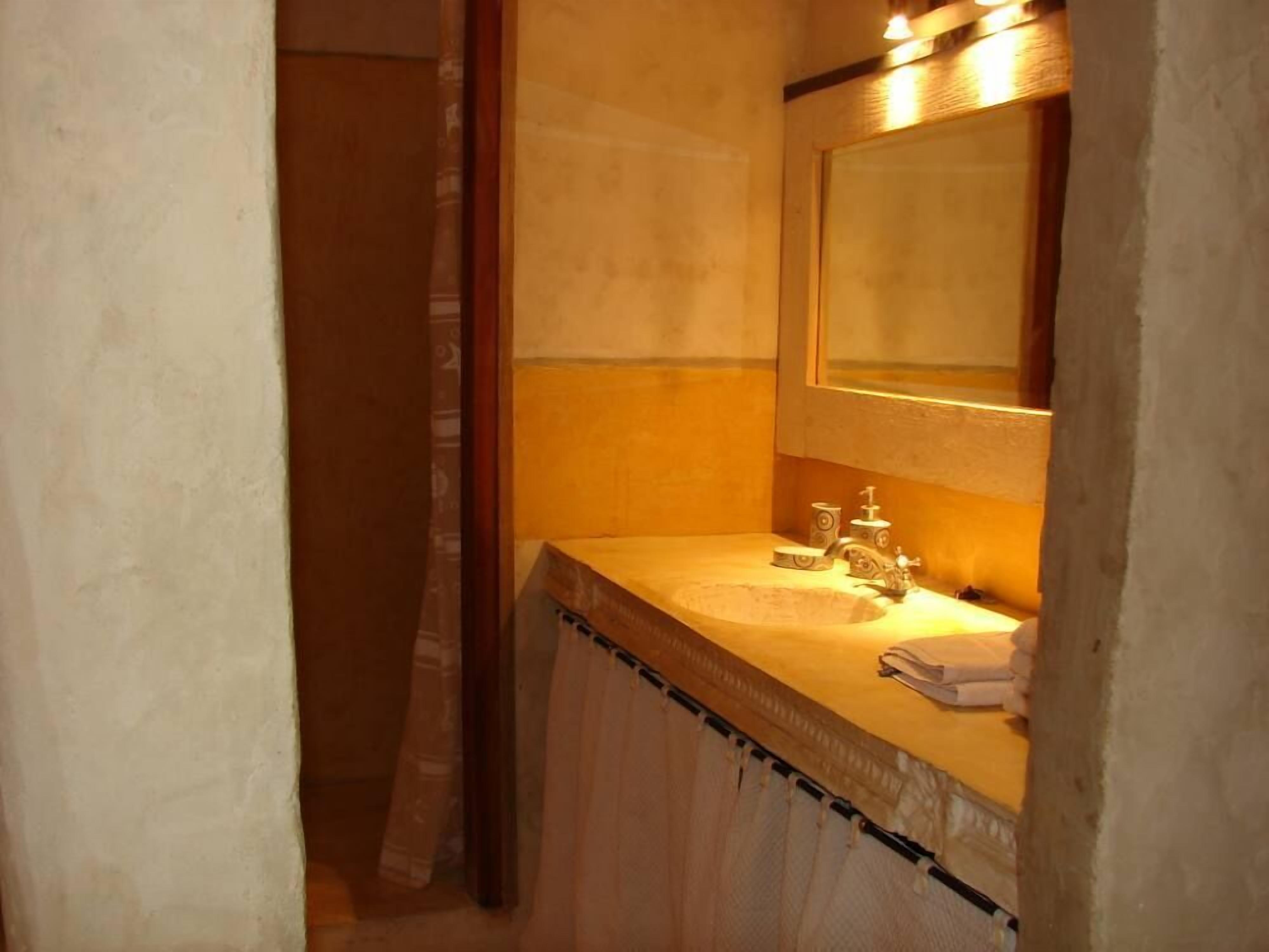 A small bathroom with a sink, mirror, and towel rack.
