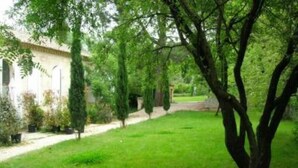 Un jardín con un sendero que lleva a un edificio de fachada blanca y columnas.