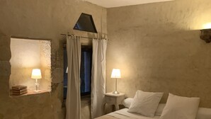 Un dormitorio con cama, dos lámparas de noche, una mesita y un ventanal con cortinas.