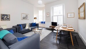 A modern living room with a sofa, coffee table, and dining table set up.