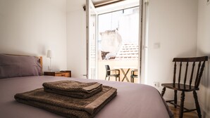 Una camera da letto con un letto, una sedia e un tavolo con vista all'esterno.