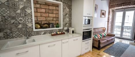 A modern kitchen with white cabinets, a built-in brick backsplash, and a wooden floor.