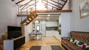 Un soggiorno moderno con televisione, divano e scala che conduce verso una cucina.
