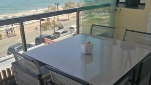 A modern dining area with a large table and chairs, overlooking a beach and street. - Whim Apartment. Front line beach, 2 bedrooms, 2 bath, Spa. Wifi. English TV (Fuengirola)