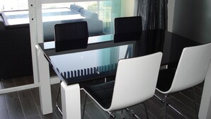 A modern office space with a glass table and two white chairs, a black desk, and a view of the city through large windows. - Whim Apartment. Front line beach, 2 bedrooms, 2 bath, Spa. Wifi. English TV (Fuengirola)