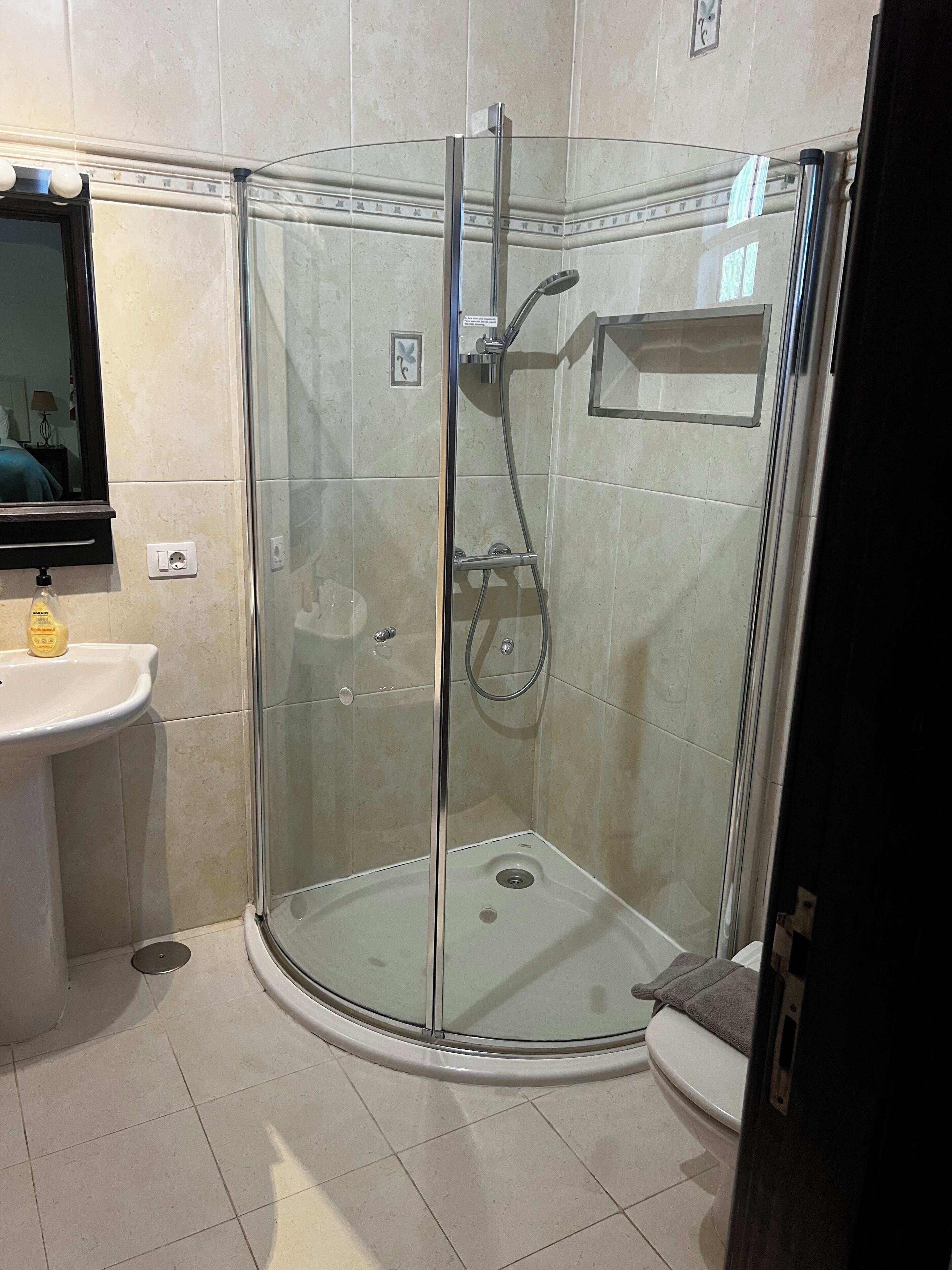 A glass-enclosed shower stall with a white sink and a mirror above it.