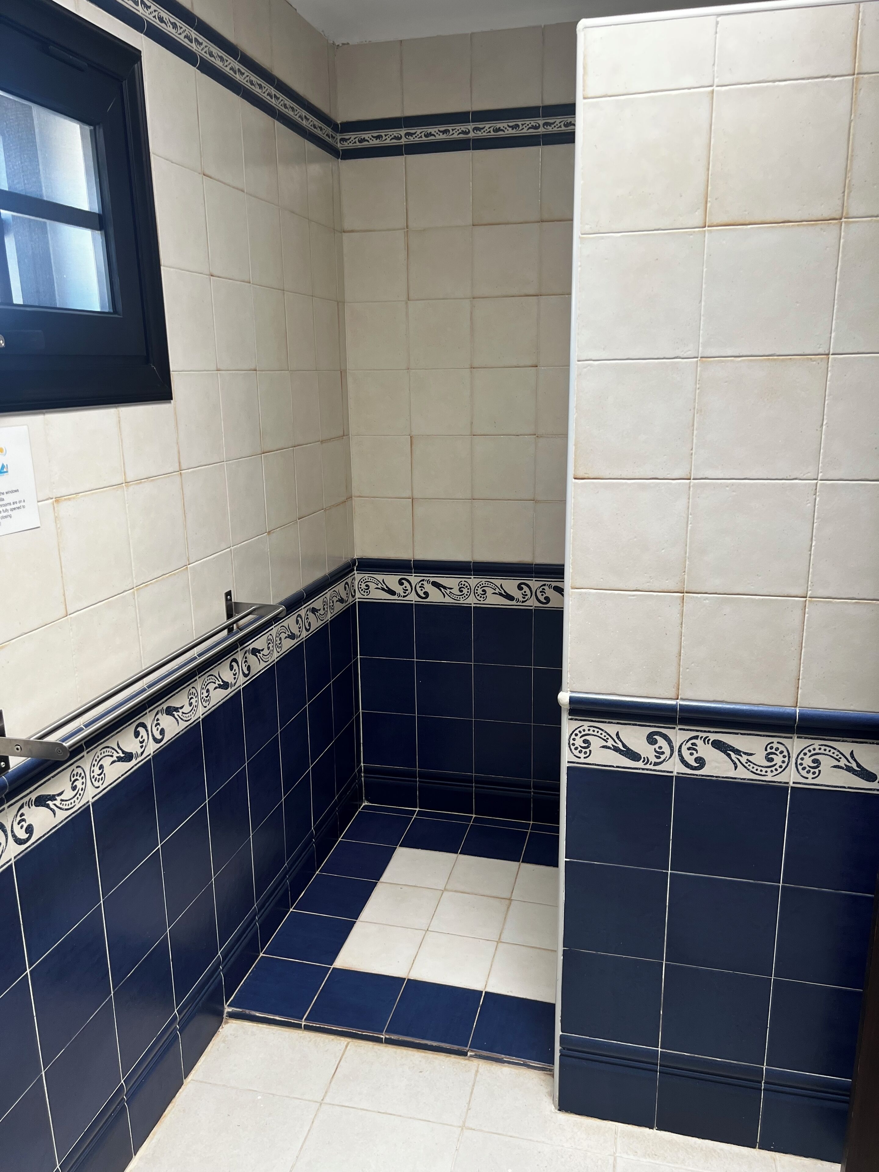 Un baño con piso de cerámica, una ventana y un perchero.