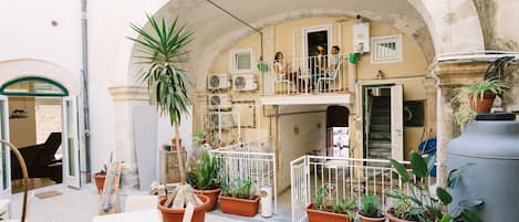 Un cortile con zona relax, piante in vaso e una scala che conduce a un piano superiore.