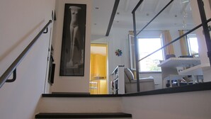 A staircase with a metal handrail leading to a room with a dining area, a chair, and a window. - Architectural designed  central apartment a few steps from the beaches. PARKING. (sestri levante)