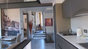 A modern kitchen with a built-in oven, a dining area with a table and chairs, and a staircase leading to an upper level. - Architectural designed  central apartment a few steps from the beaches. PARKING. (sestri levante)