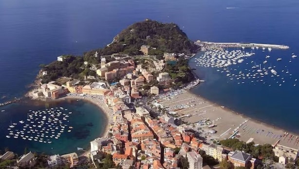 An aerial view of a coastal town with a historic center, a marina with numerous boats, and a beach area. - Architectural designed  central apartment a few steps from the beaches. PARKING. (sestri levante)