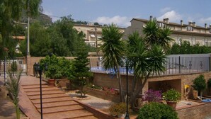 Un quartier résidentiel doté d’un chemin pavé, d’un mur en briques et de divers arbustes et plantes en pot.
