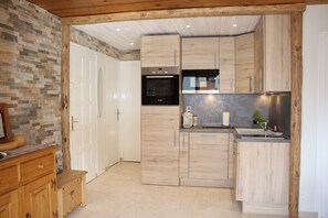 Een moderne keuken met houten kastjes, een inbouwoven en een RVS spoelbak.