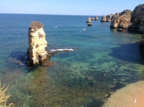 A coastal landscape with clear waters, rocky formations, and a sandy beach. - Cosy Apartment near the beach - Enjoy the summer almost all year (Lagos)
